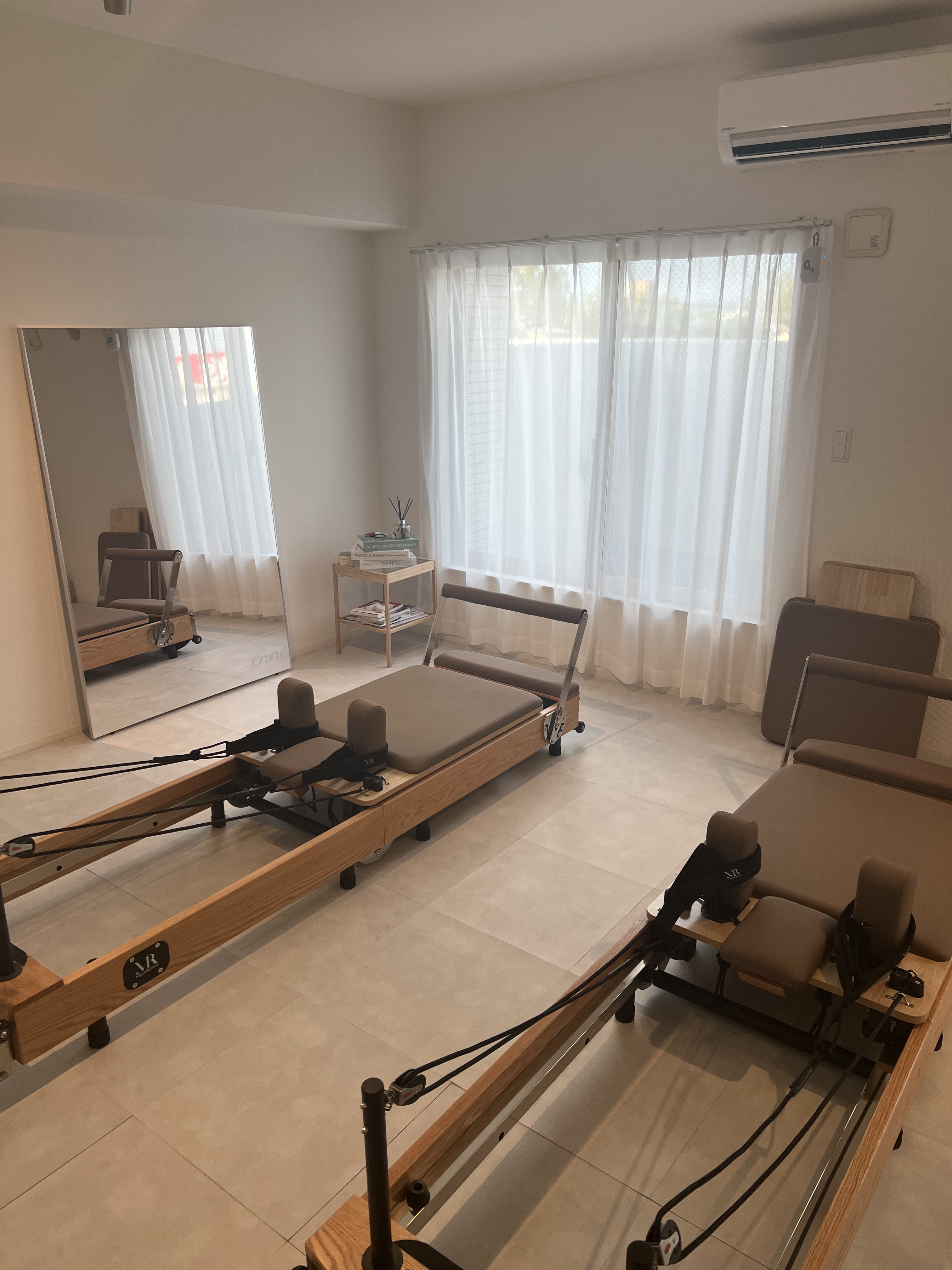 木製リフォーマーが並ぶPilates enneの明るいスタジオ